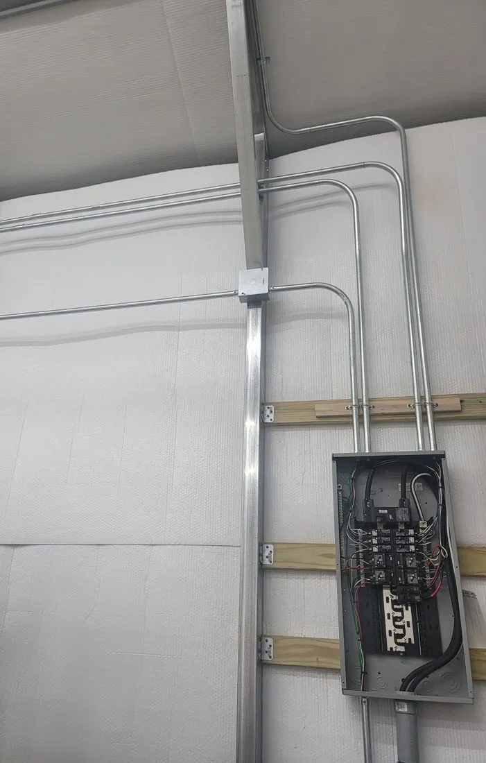 New panel and surface conduit installed in a metal workshop